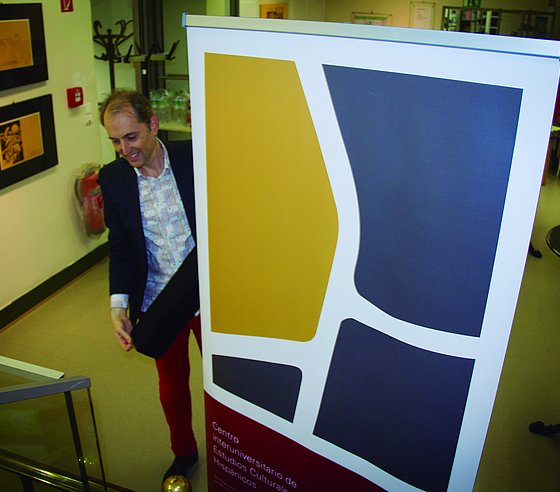 Matei Chihaia, der das Spanien-Zentrums der Bergischen Universität Wuppertal und der Heinrich-Heine-Universität Düsseldorf gemeinsam mit Ursula Hennigfeld leitet, mit dem von David Laubmeier gestalteten Logo des Zentrums