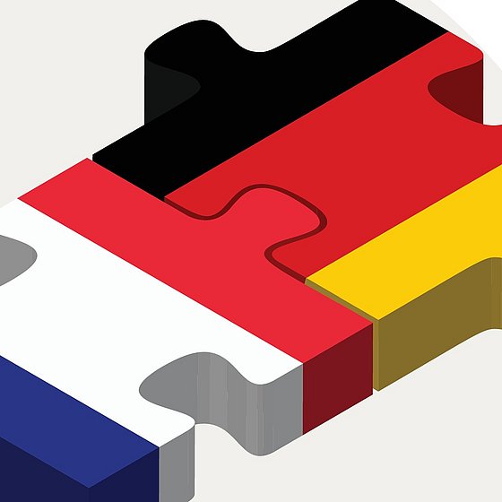 Man sieht zwei Puzzlestücke, die miteinander verbunden sind. Auf dem einen ist die französische Flagge abgebildet und auf dem anderen die deutsche Flagge
