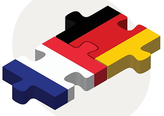 Zwei Puzzlestücke, die miteinander verbunden sind. Auf dem einen Puzzlestück ist die französische Flagge abgebildet und auf dem anderen ist die deutsche Flagge zu erkennena
